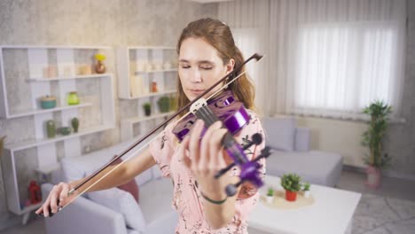 Violinist-young-woman-playing-her-purple-violin-at-home.